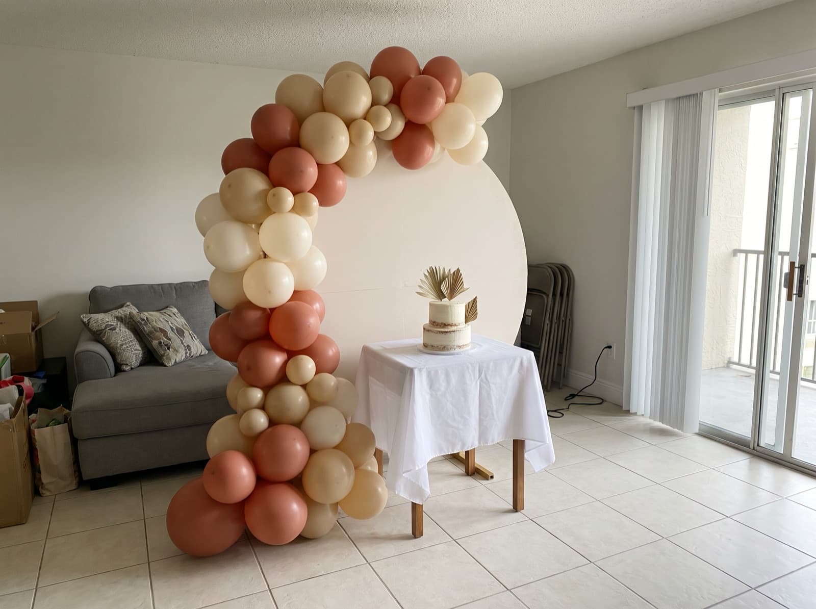 Half balloon arch swooping over a cake table in a condo