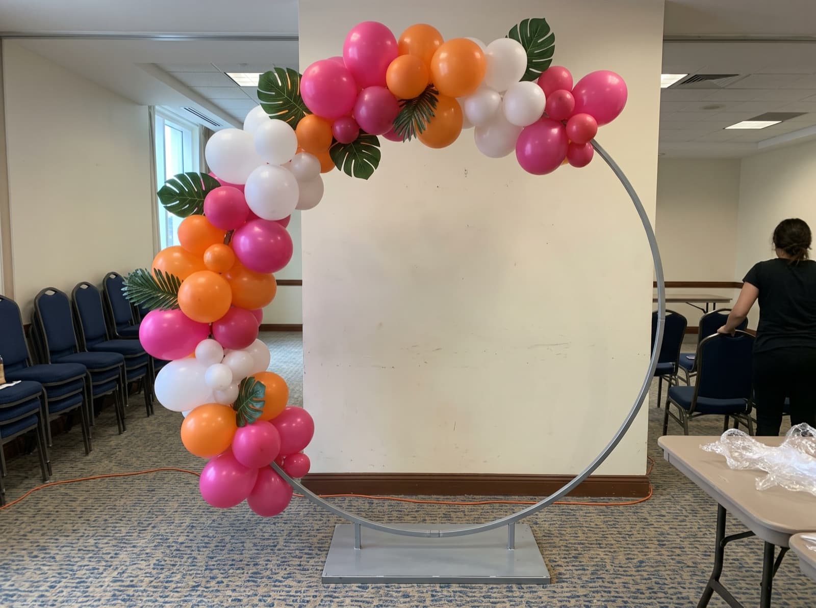 Round balloon arch with tropical leaves framing a photo spot