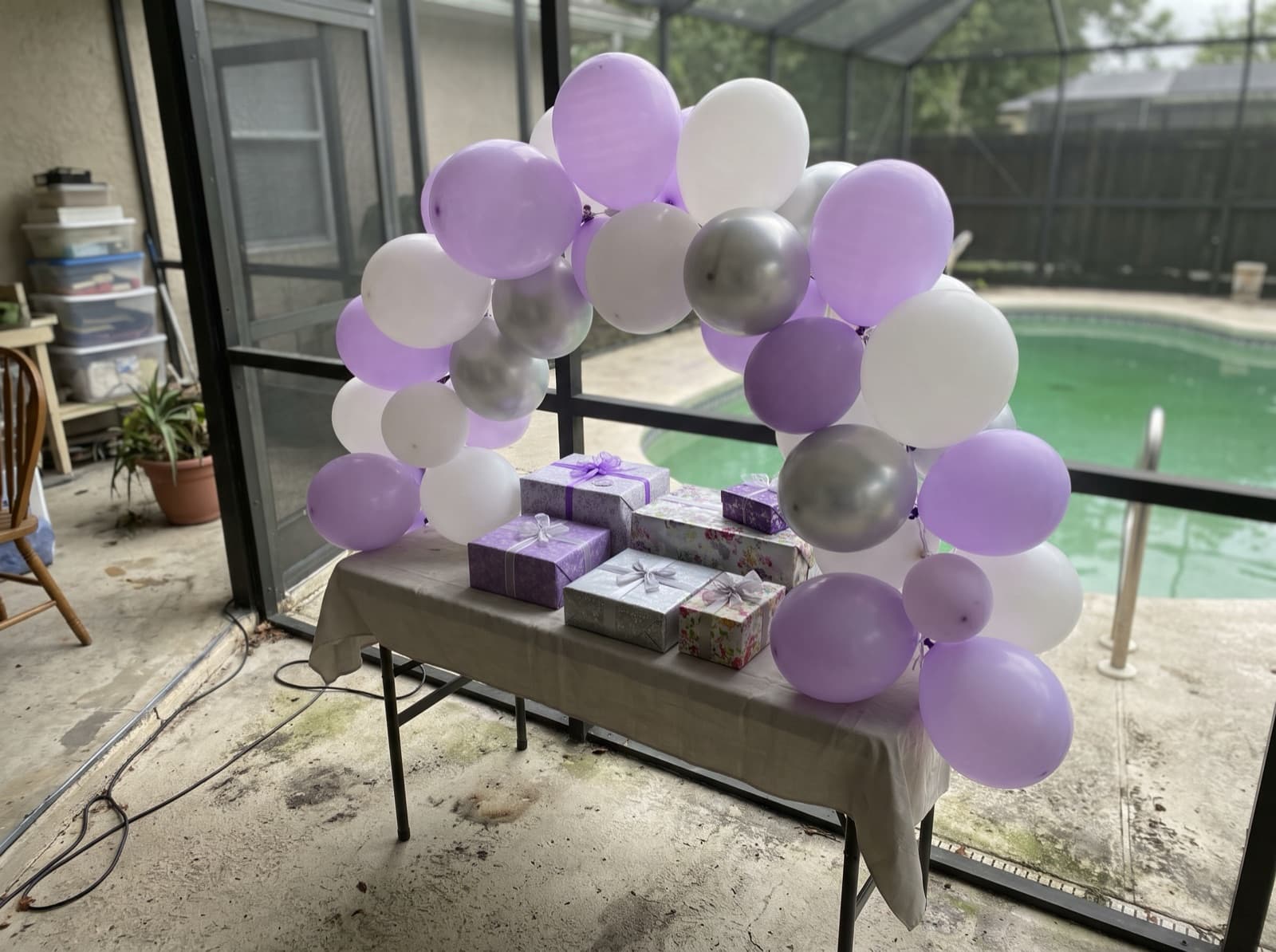 Mini tabletop balloon arch over a gift table on a pool patio