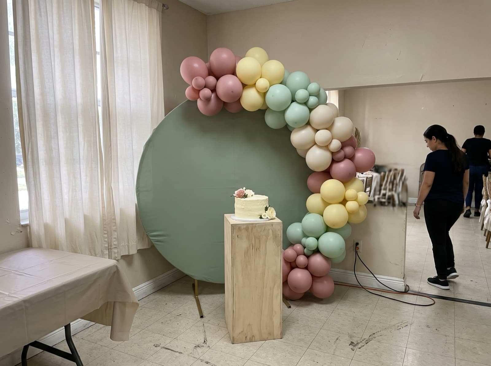 Round sage backdrop with a pastel balloon garland
