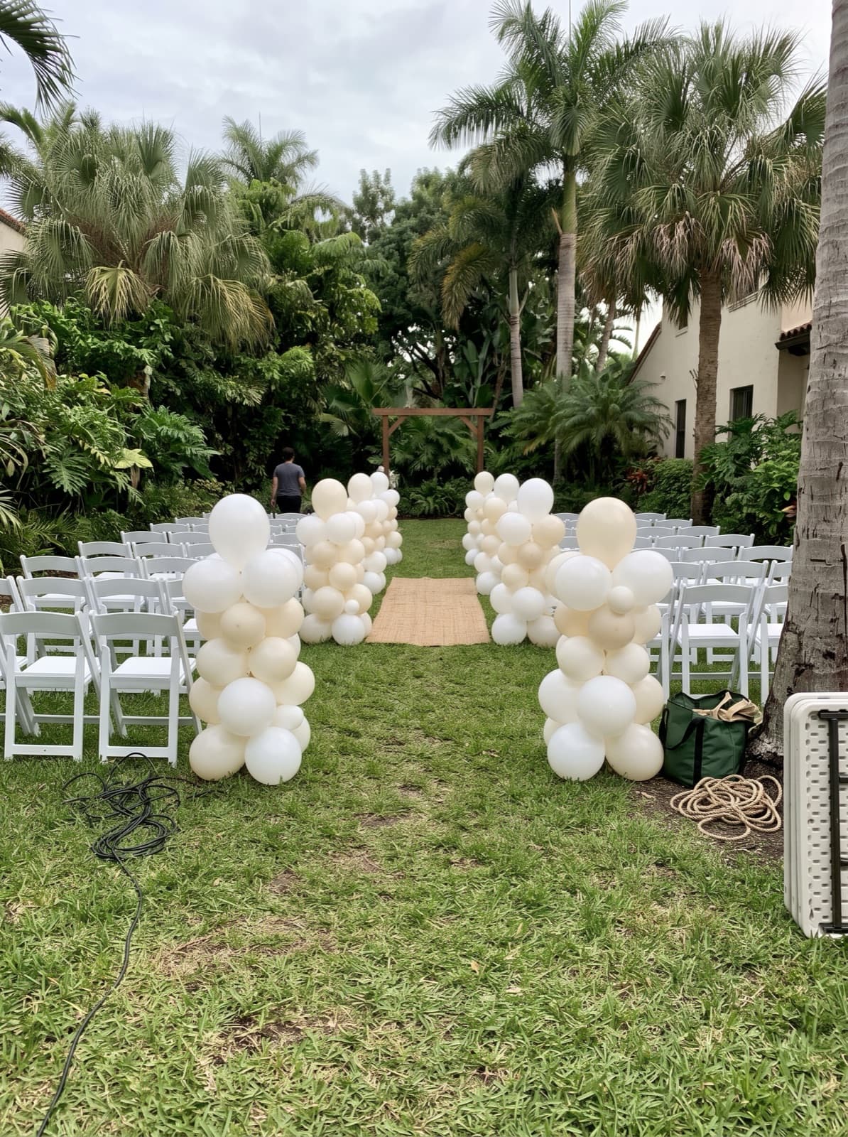 Organic balloon columns lining an outdoor ceremony aisle