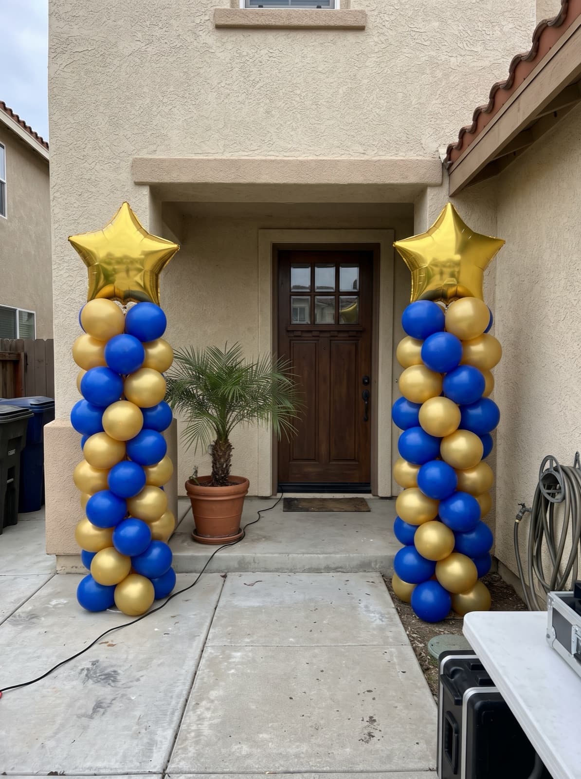Pair of spiral balloon columns in royal blue and gold with star toppers at a Miami graduation party