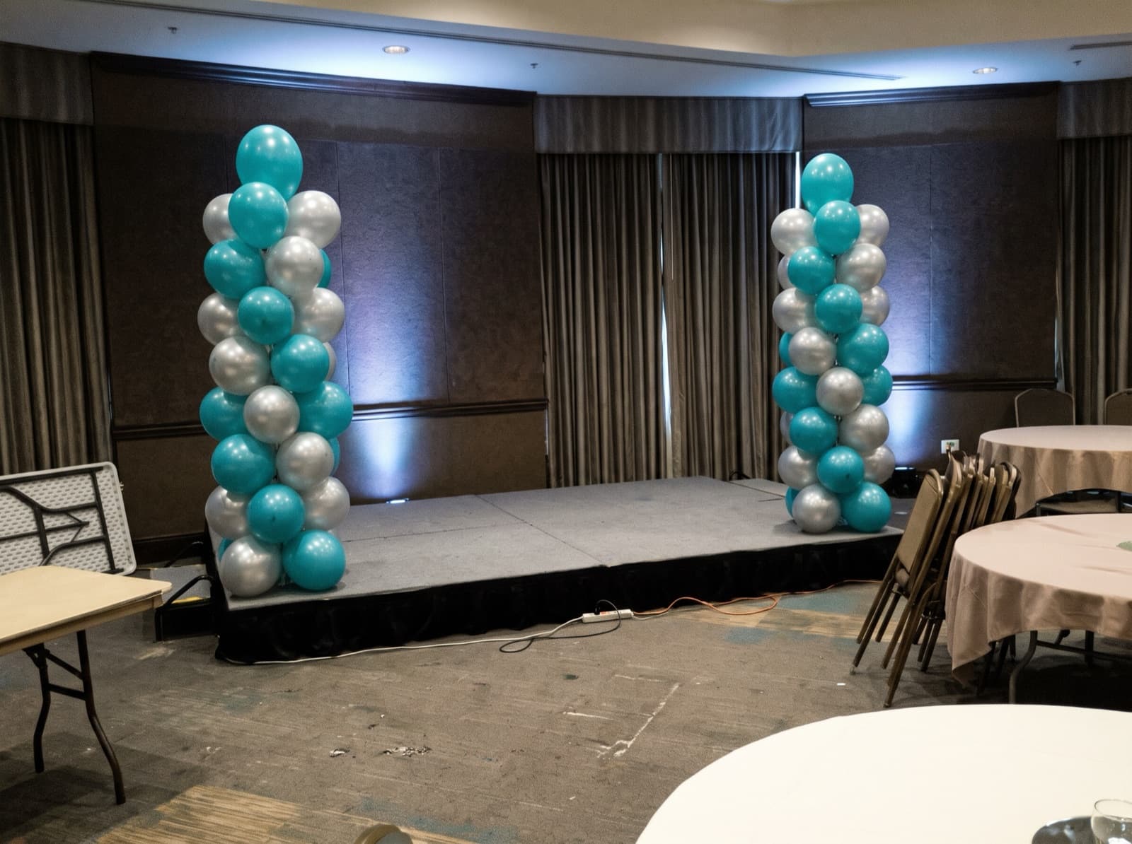 Teal and silver balloon columns framing a ballroom stage