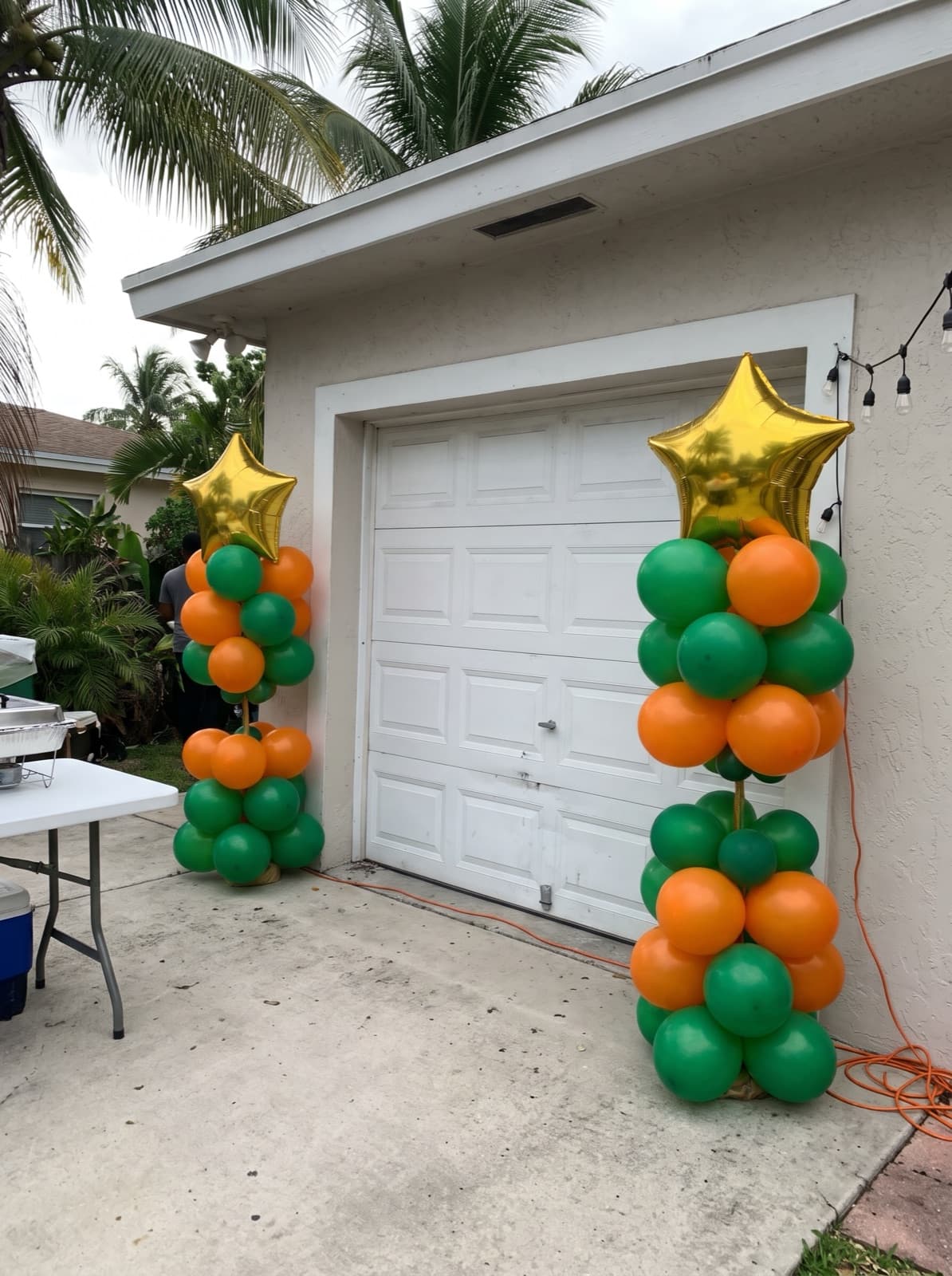 Green and orange balloon columns with gold star toppers at a grad party
