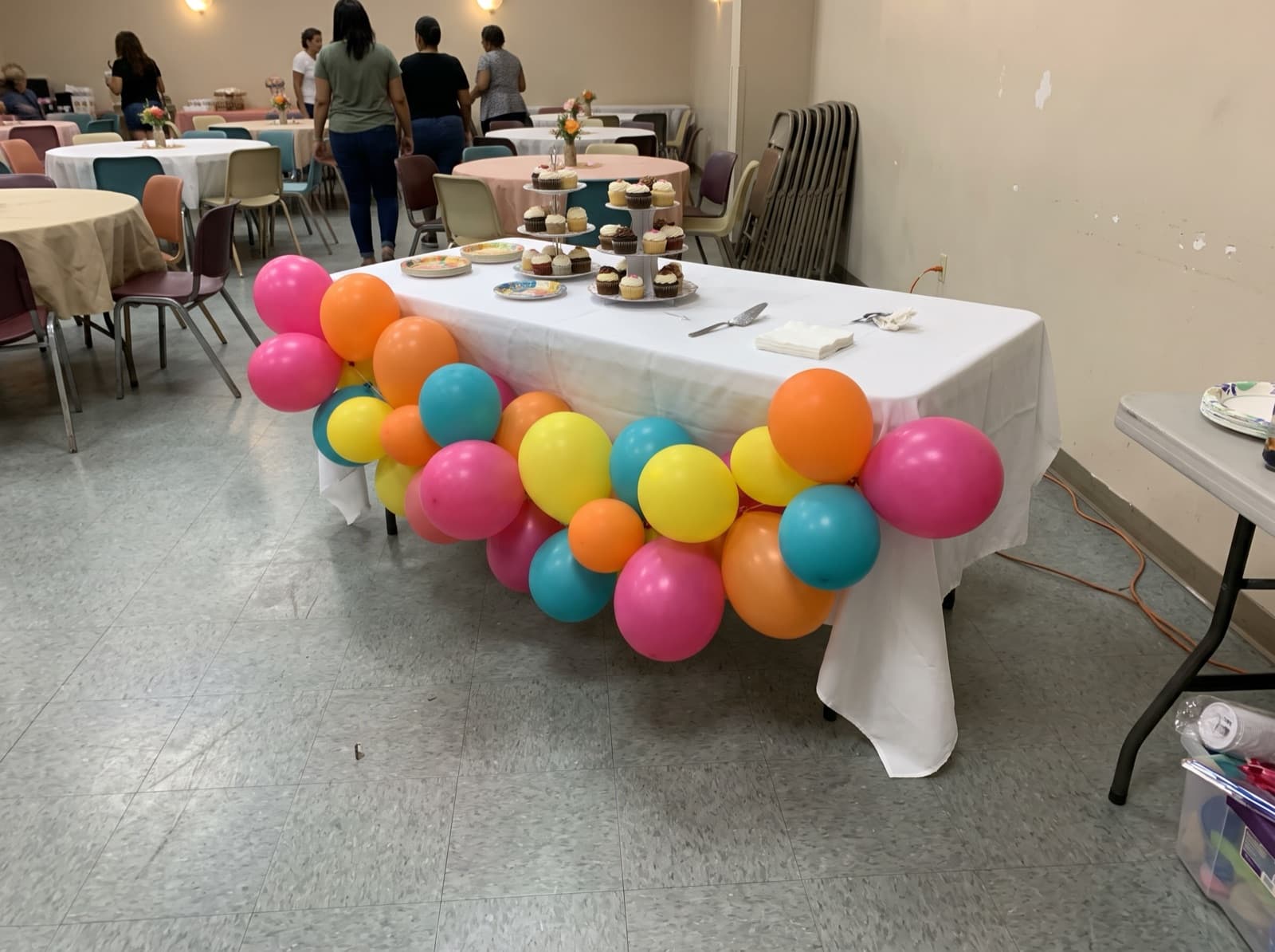 Tropical-color balloon garland along the edge of a cake table