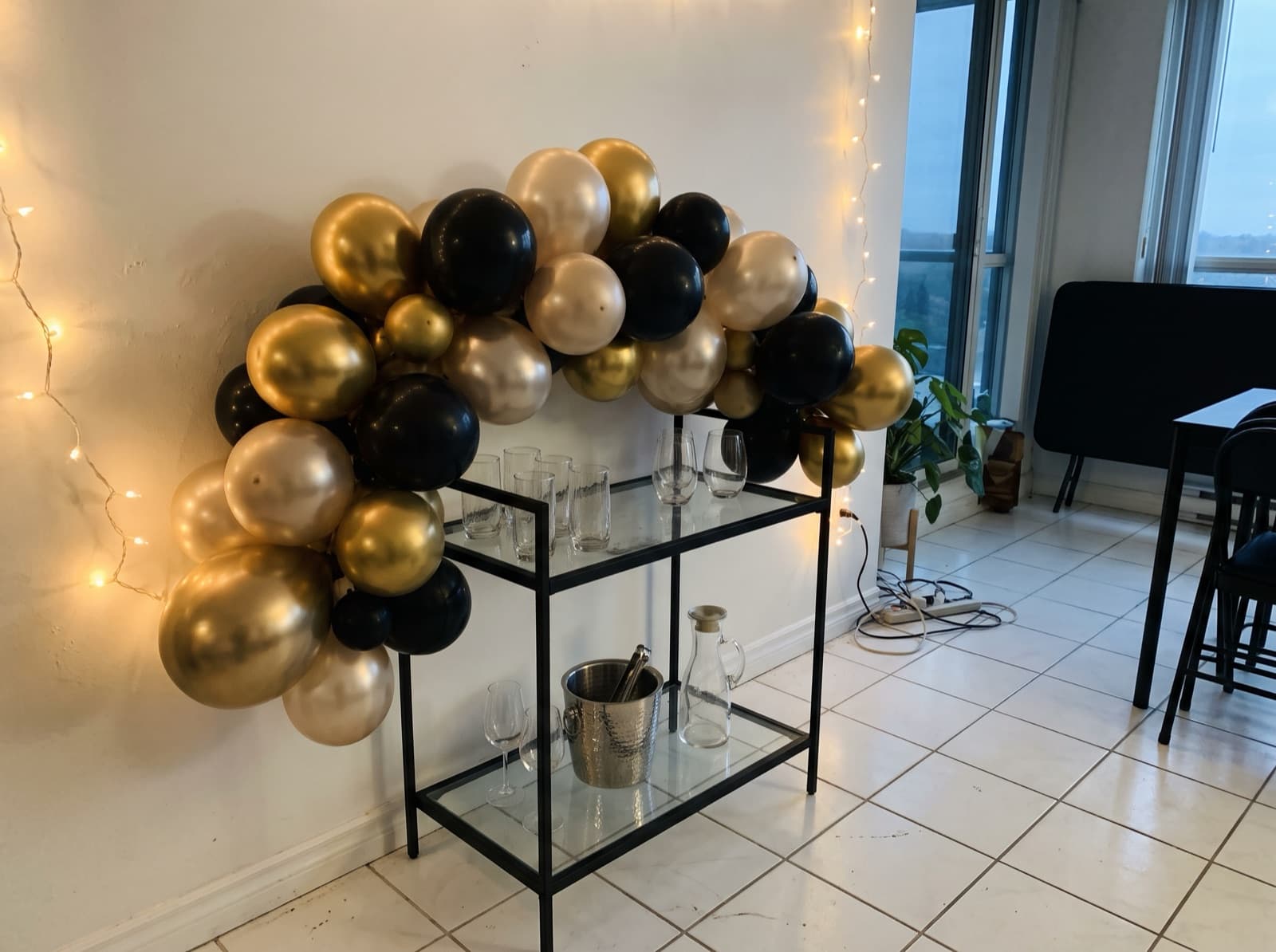 Chrome and champagne balloon garland over a bar cart for New Year's Eve