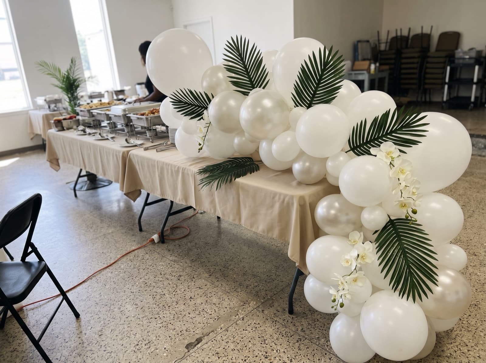Balloon garland with palm leaves and orchids along a buffet