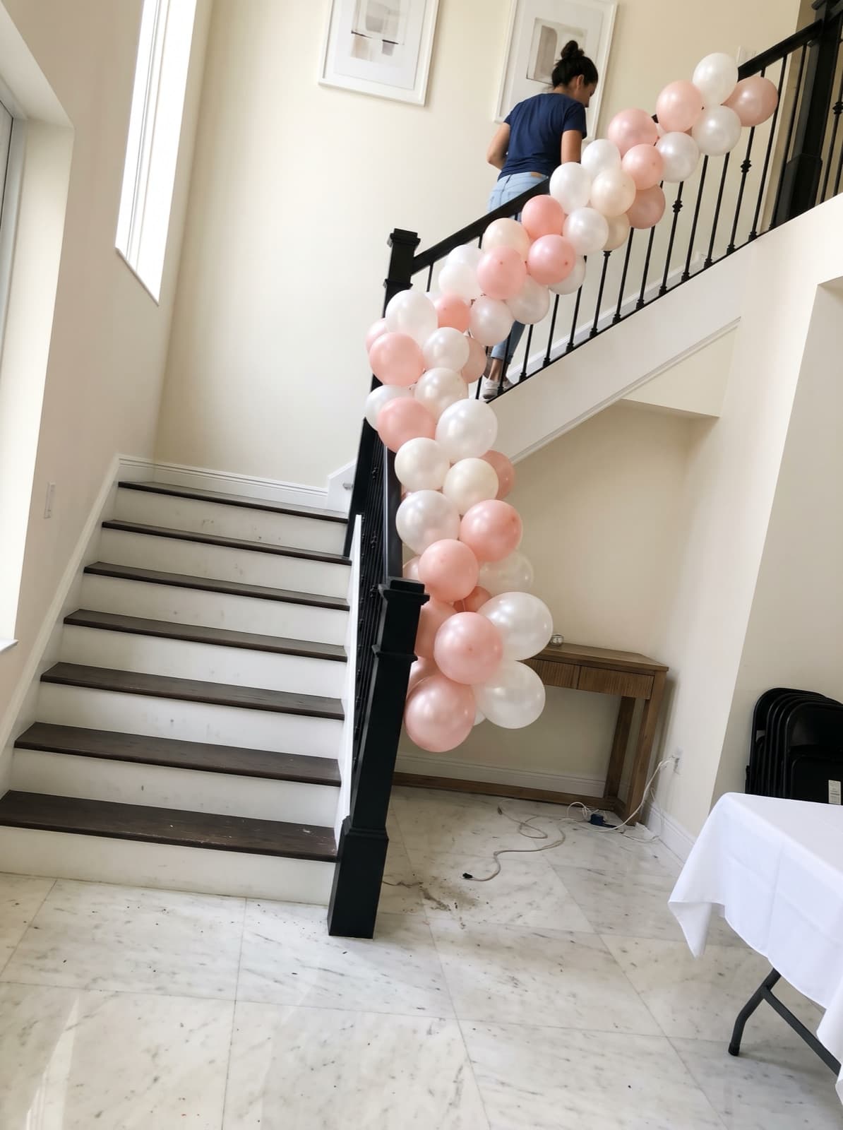 Balloon garland running down a staircase with a wrought-iron railing