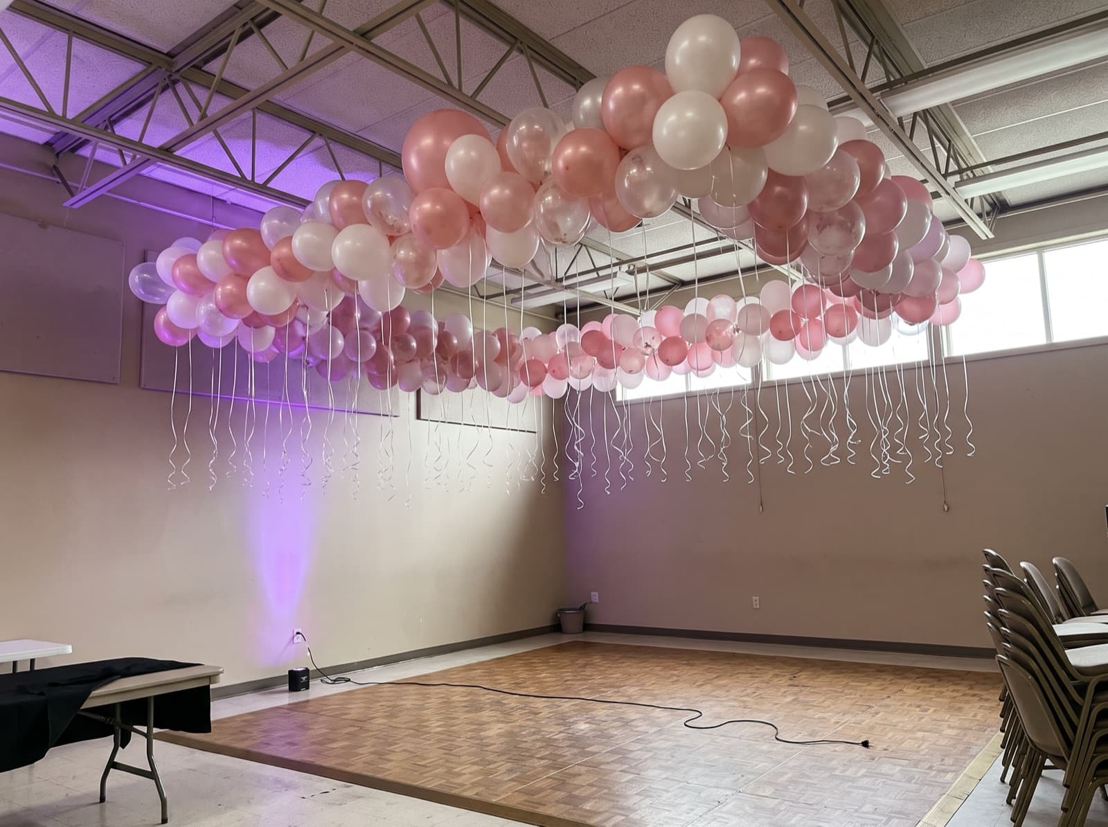 Balloon ceiling of blush and white balloons over a dance floor