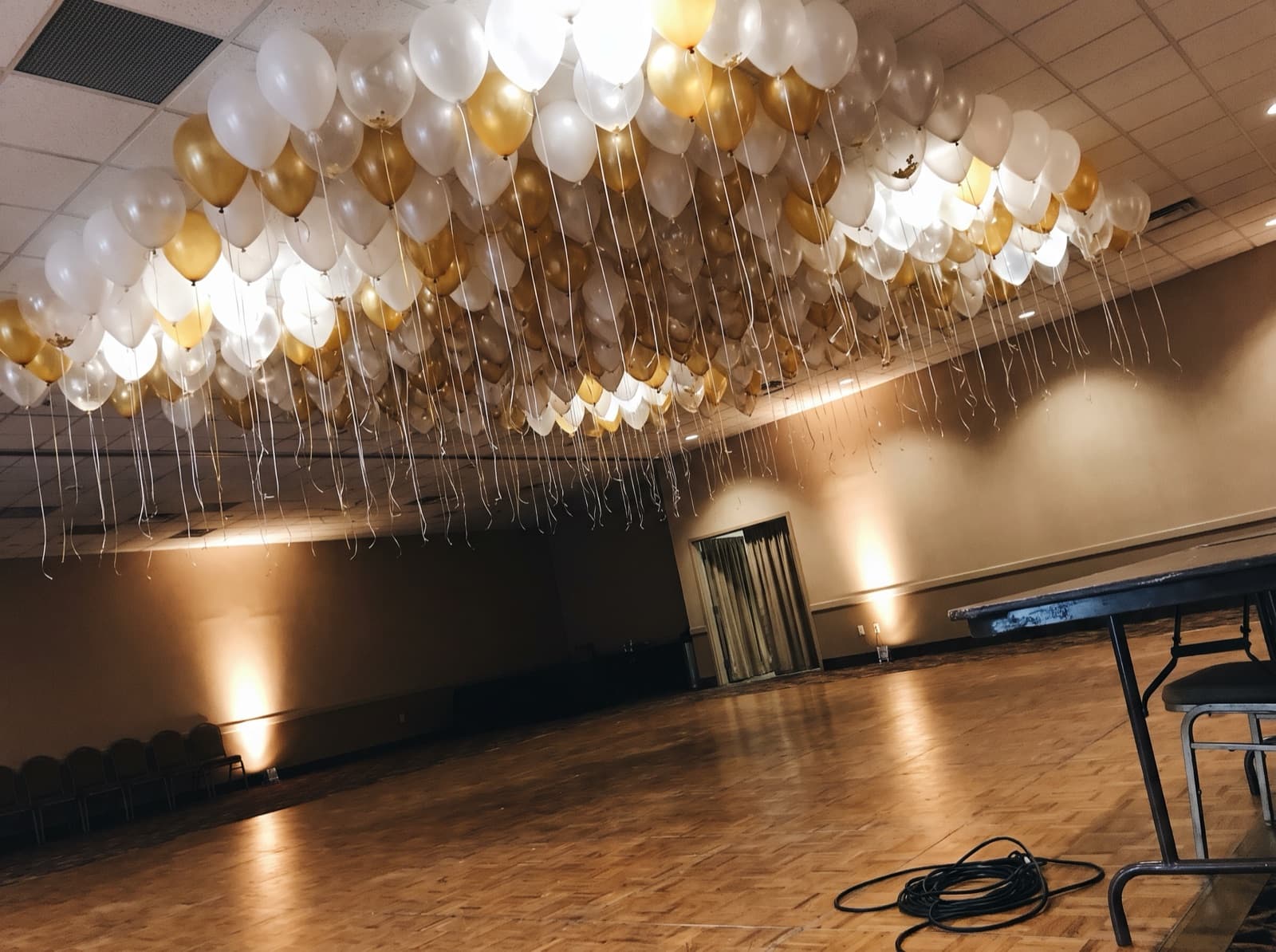 Looking up at a white, clear and gold balloon ceiling above a Miami hotel ballroom dance floor
