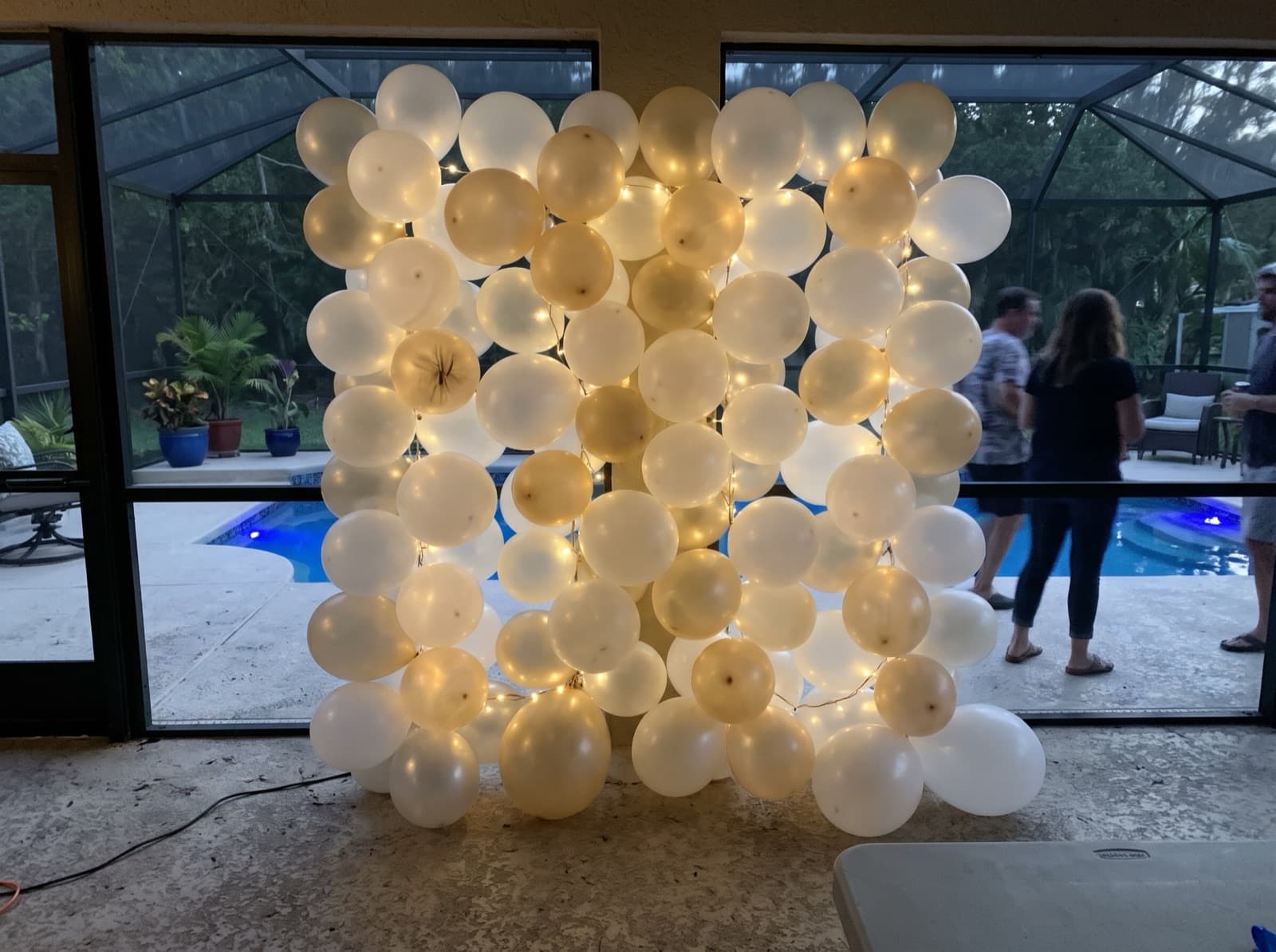 Balloon wall with string lights on a screened pool patio